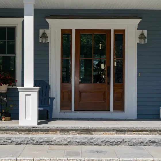 Finished front entry with mahogany door and blue shingle siding