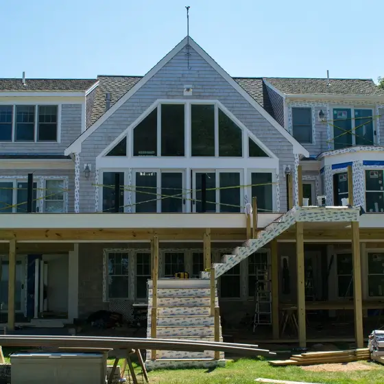 Full rear view of a Cape Cod home with new deck framing underway