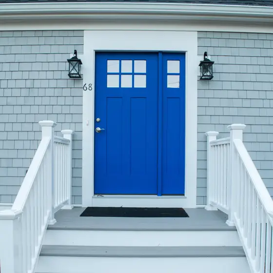 Blue front door with white staircase and shingle siding