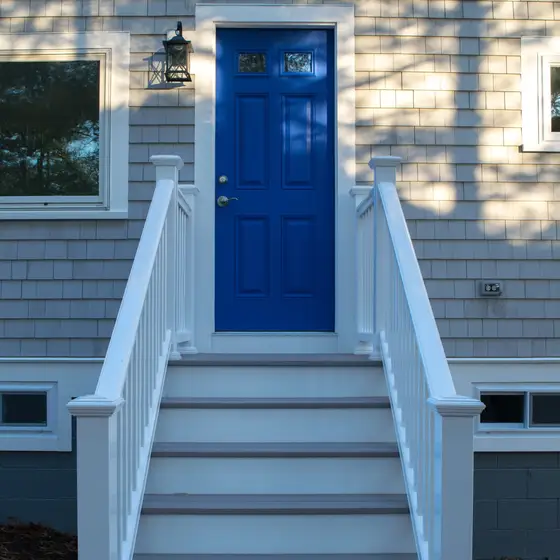 Close-up of a blue front door with black lantern sconces