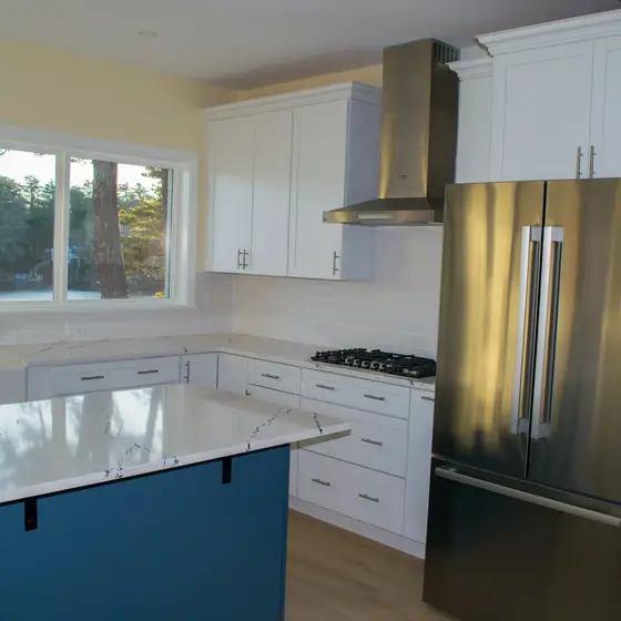 Renovated kitchen with white cabinets, stainless appliances and blue island
